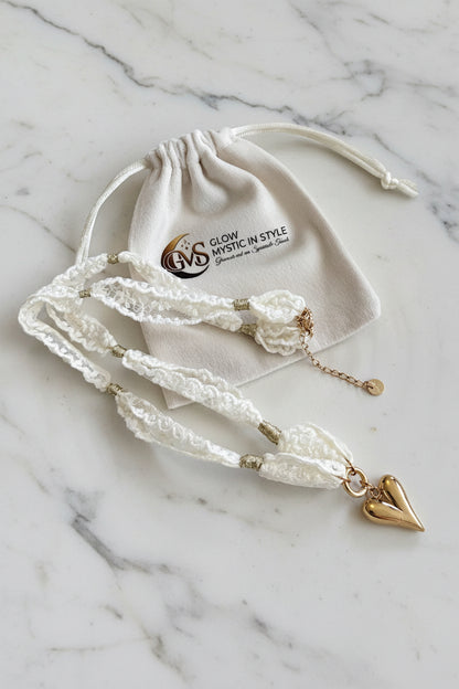 Glow Mystic Lace Choker ketting met goud hart hanger gepresenteerd op een marmeren plaat naast het luxe velvet zakje.