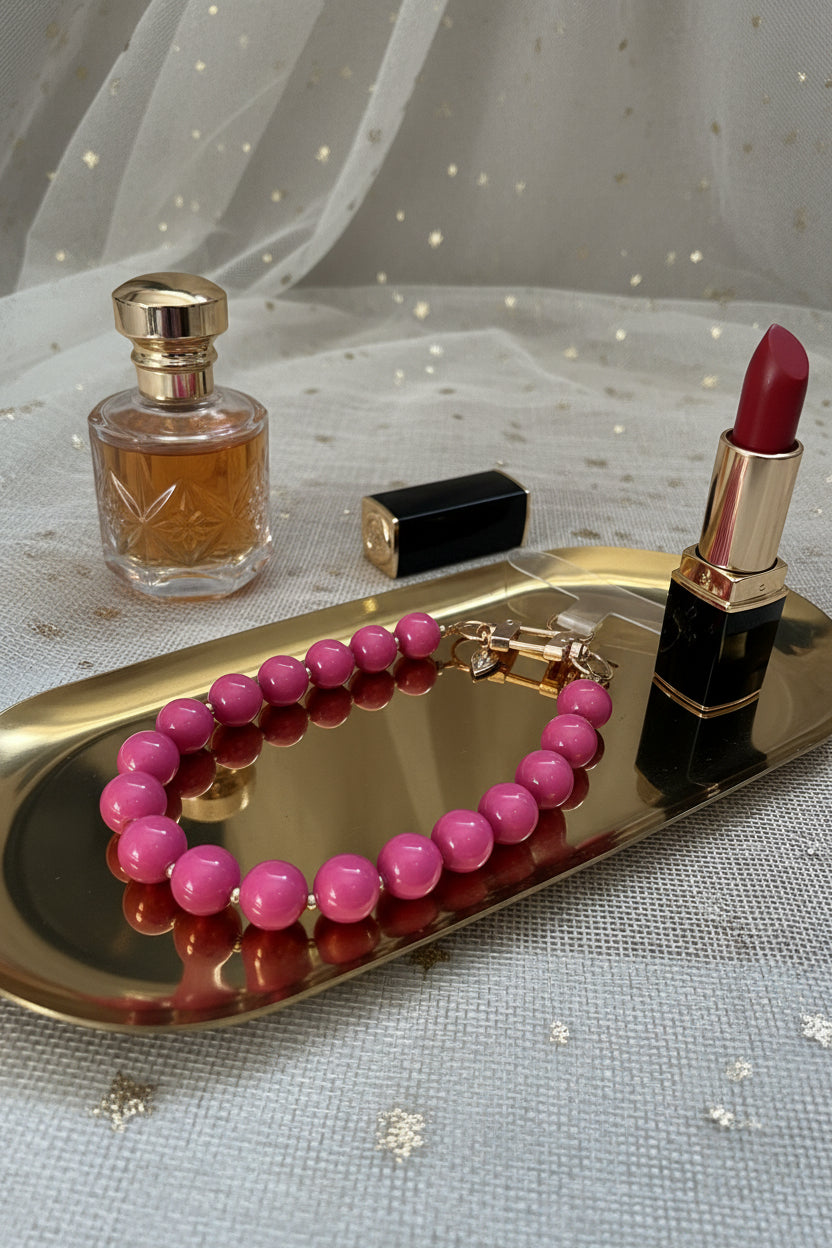 zijaanzicht van een fuchsia roze telefoonkoord op een goudkleurige schaal met 2 lifestyle producten eromheen.