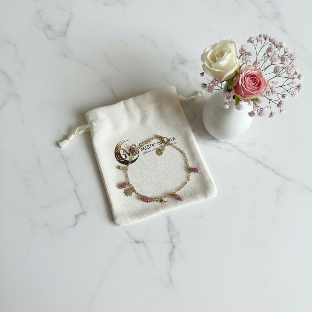armbandje met fuciakralen  op een Glow Mystic in Style velvet zakje met een vaasje bloemen ernaast op een marmeren plaat.