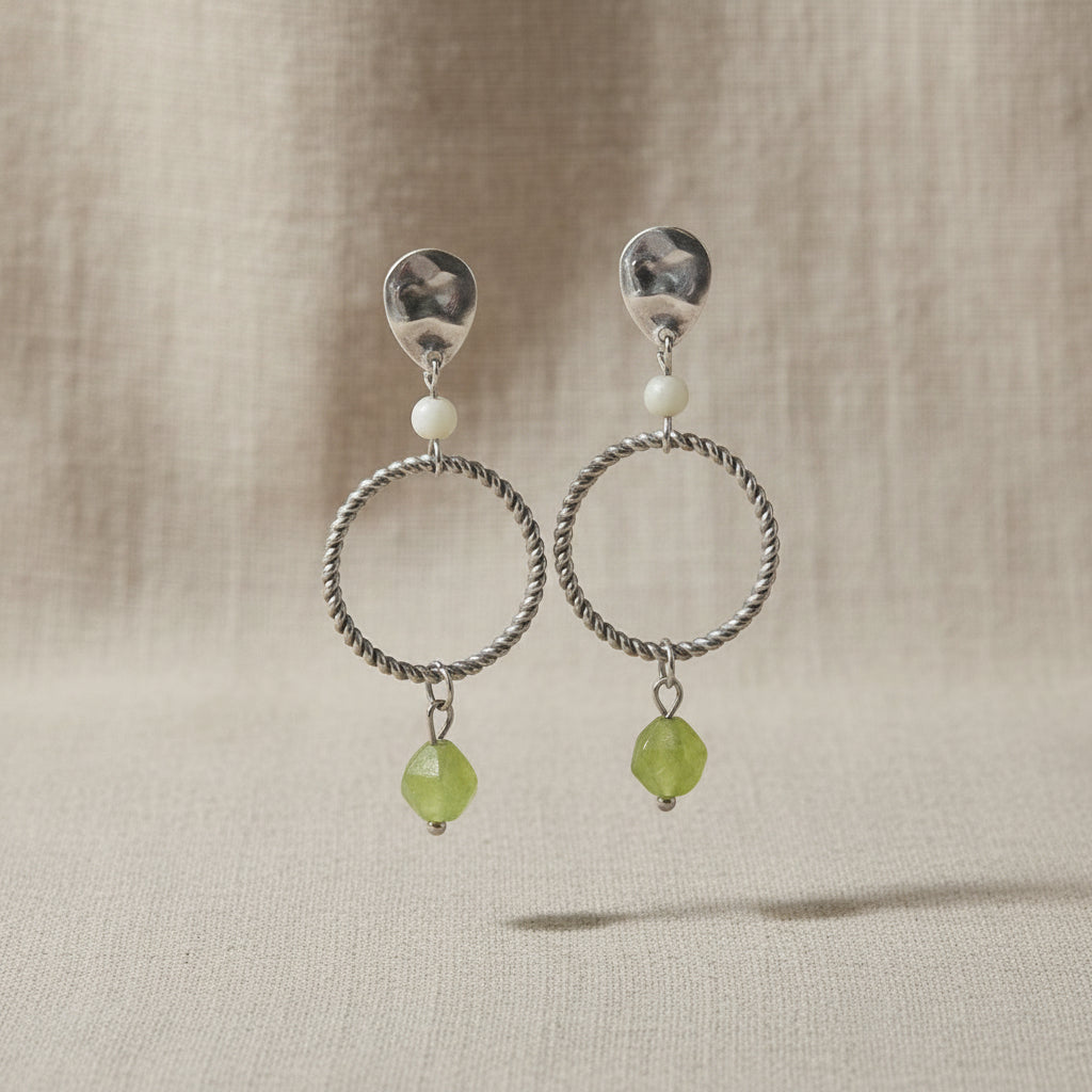 Detail van peridot edelsteen en maansteen in zilveren oorbellen