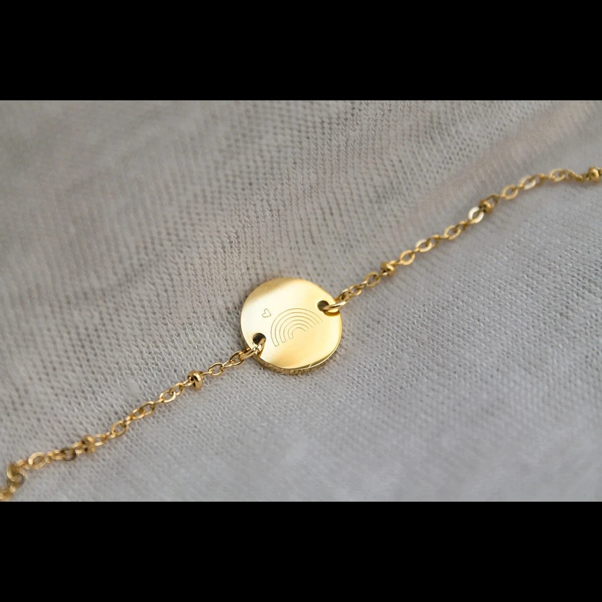 Detail van regenboogbaby armband met subtiele gravure van regenboog en hartje