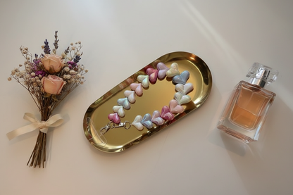 Glow Mystic in Style hartjes telefoonkoord van acryl op een goudkleurige schaal met lifestyle producten eromheen.