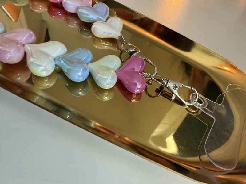 Glow Mystic in Style gekleurd acryl hartjes telefoonkoord op een goudkleurige schaal.