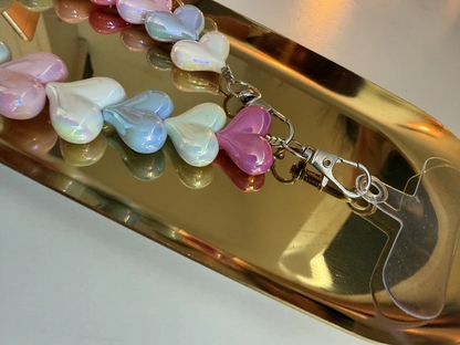 Glow Mystic in Style gekleurd acryl hartjes telefoonkoord op een goudkleurige schaal.