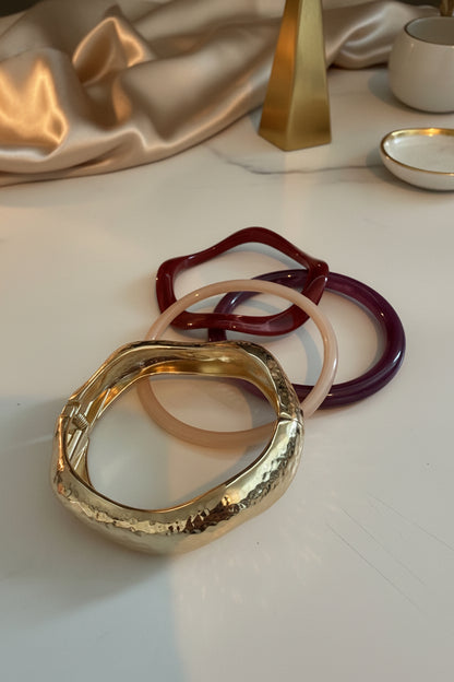 Glow Mystic in Style goudkleurige scharnier bangle armband met golvend design gepresenteerd met een lifestyle setting.