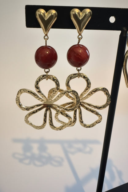 Glow Mystic in Style gouden statement oorbellen met hartje en bloem aan sieradenstandaard