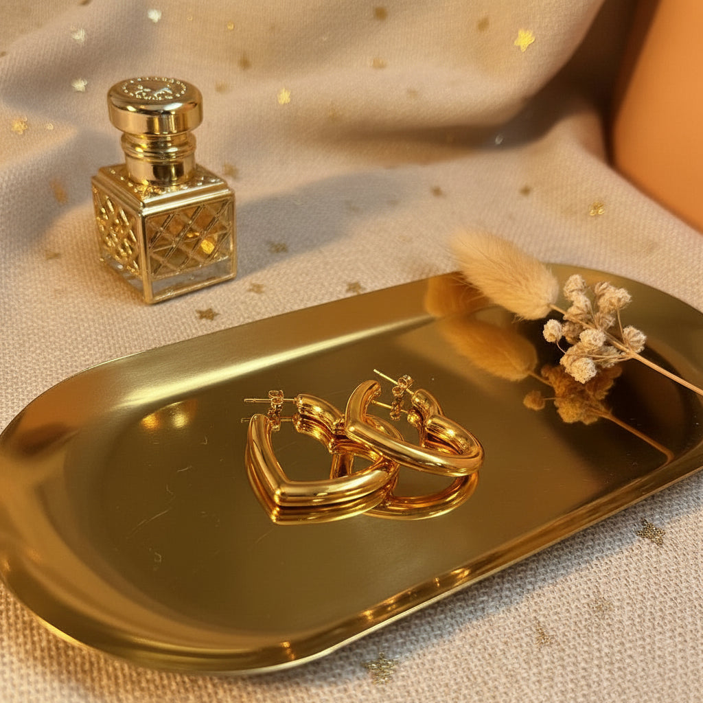 Close-up van Glow Mystic in Style gouden hart oorbellen op gouden tray