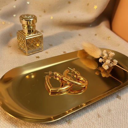 Close-up van Glow Mystic in Style gouden hart oorbellen op gouden tray