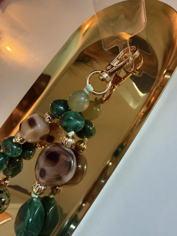 Glow Mystic in Style groene kralen telefoonketting met luipaardprint opeen goudkleurige schaal