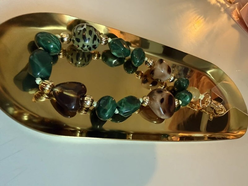 Glow Mystic in Style groene kralen telefoon charm met goudkleurige sluiting  op een goudkleurige schaal.