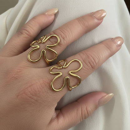 "Twee goudkleurige RVS bloem ringen van Glow Mystic in Style gedragen aan de hand, laten zien hoe de ringen staan en combineren."