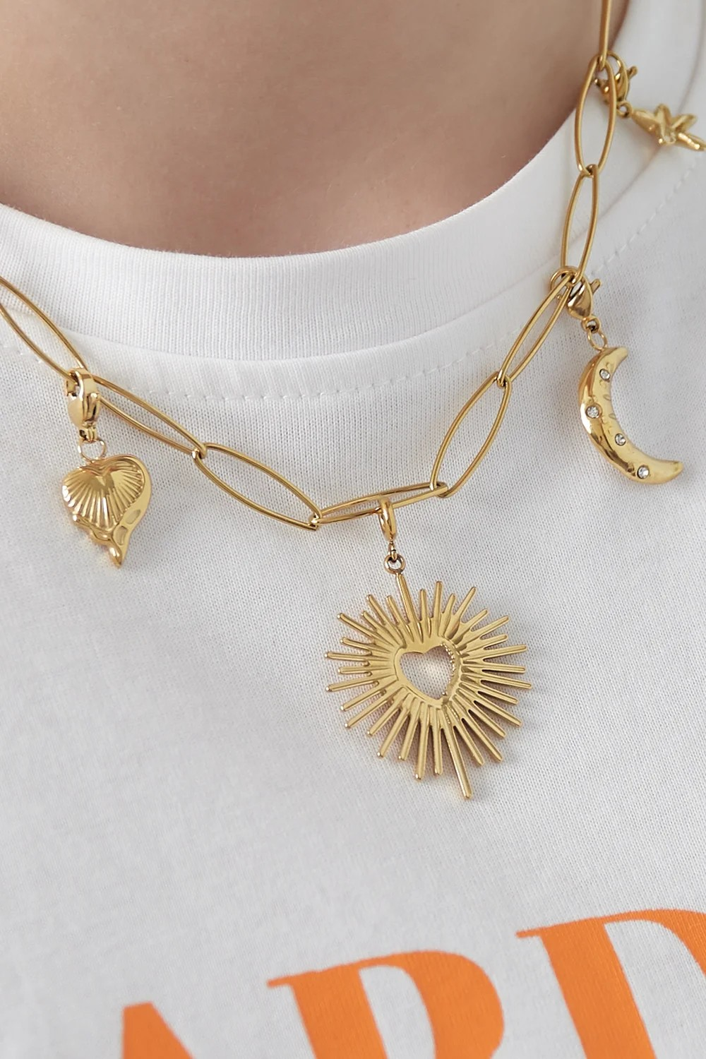 Gouden zon hart bedel bevestigd aan een schakelketting van roestvrij staal.