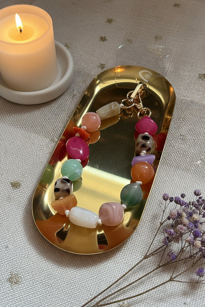 Mooie grote acryl kralen telefoonkoord van Glow Mystic in Style op een gouden schaal met lifestyle producten eromheen.