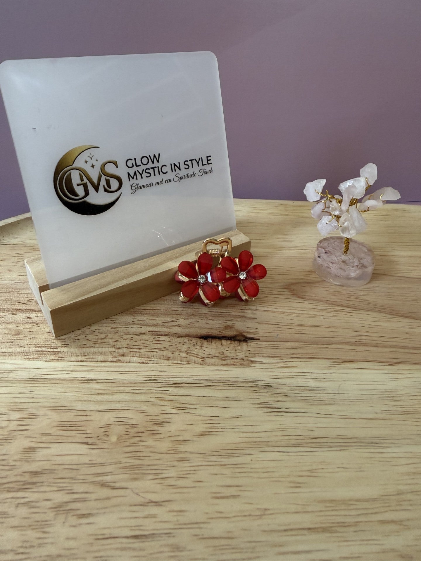 Gouden mini haarklem met twee rode bloemetjes en strass-steentjes op houten schaal met een display ernaast van Glow Mystic in Style.