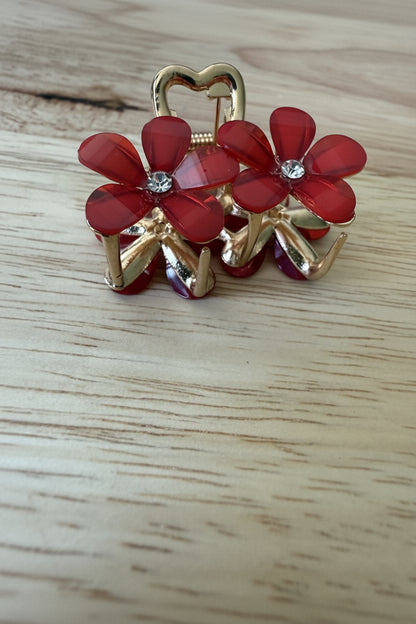 Close up van mini haarklem goed met rode bloemen en strass steentje op een houtkleurige achtergrond.