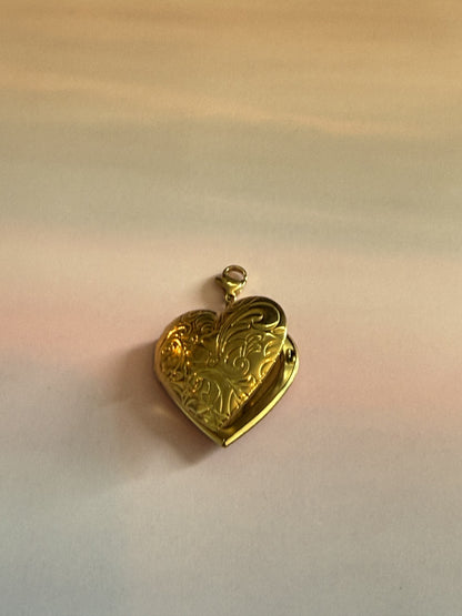 Gouden RVS hart medaillon bedel met fotovak voor ketting op gekleurde achtergrond.