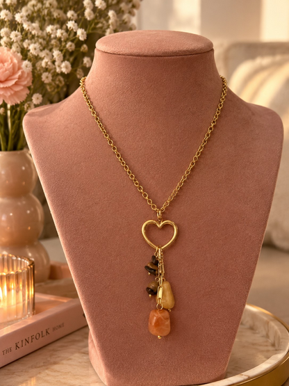 Glow Mystic in Style gouden stainless steel ketting met open hart en bruine kralenbedel gepresenteerd op roze buste