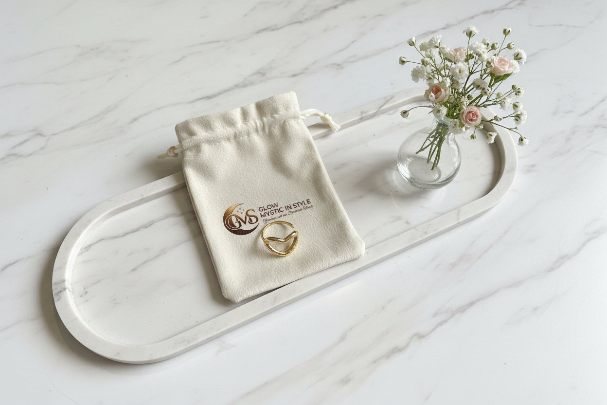 Minimalistische gouden ring op een gepersonaliseerd sieraden zakje, geplaatst op een ovaal armeren plateau met subtiele bloemen,