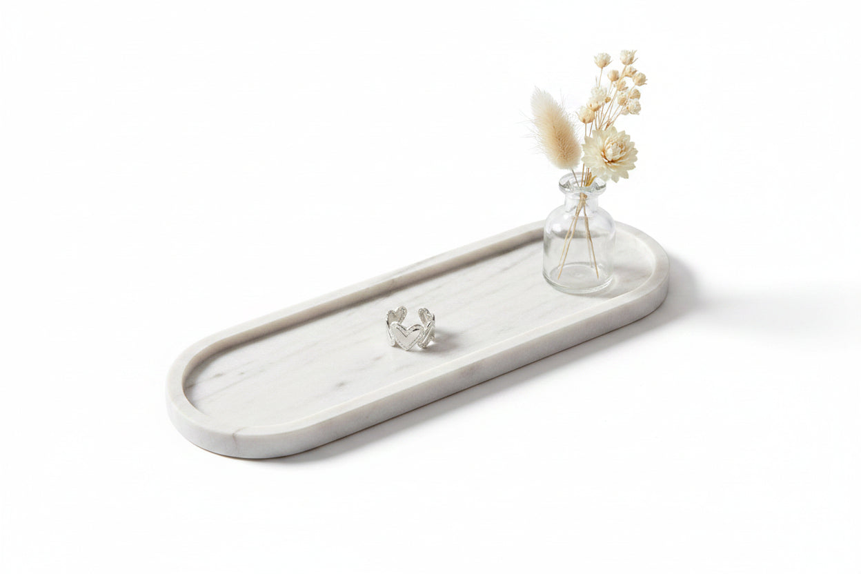 Zilveren open ring op een ovale marmeren tray met een klein vaasje droogbloemen.