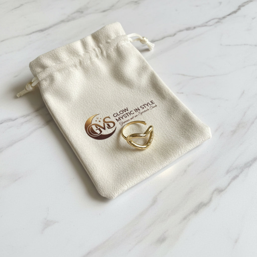 Elegante goudkleurige RVS hart ring liggend op een wit Glow Mystic in Style sieradenzakje op een luxe marmeren plaat.