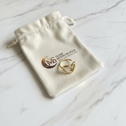 Elegante goudkleurige RVS hart ring liggend op een wit Glow Mystic in Style sieradenzakje op een luxe marmeren plaat.