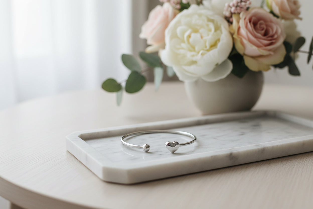 Hart bangle armband als mock up op een marmeren schaal met bloem op de tafel.