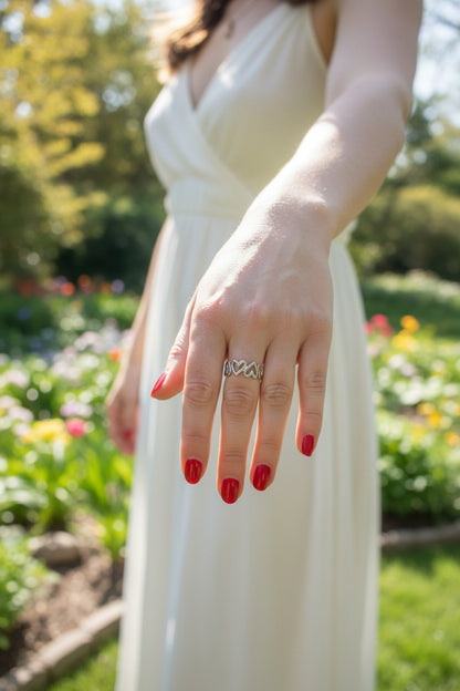 "Elegante zilverkleurige RVS ring met hartjes gedragen door een vrouw in een witte jurk in een zonnige tuin."