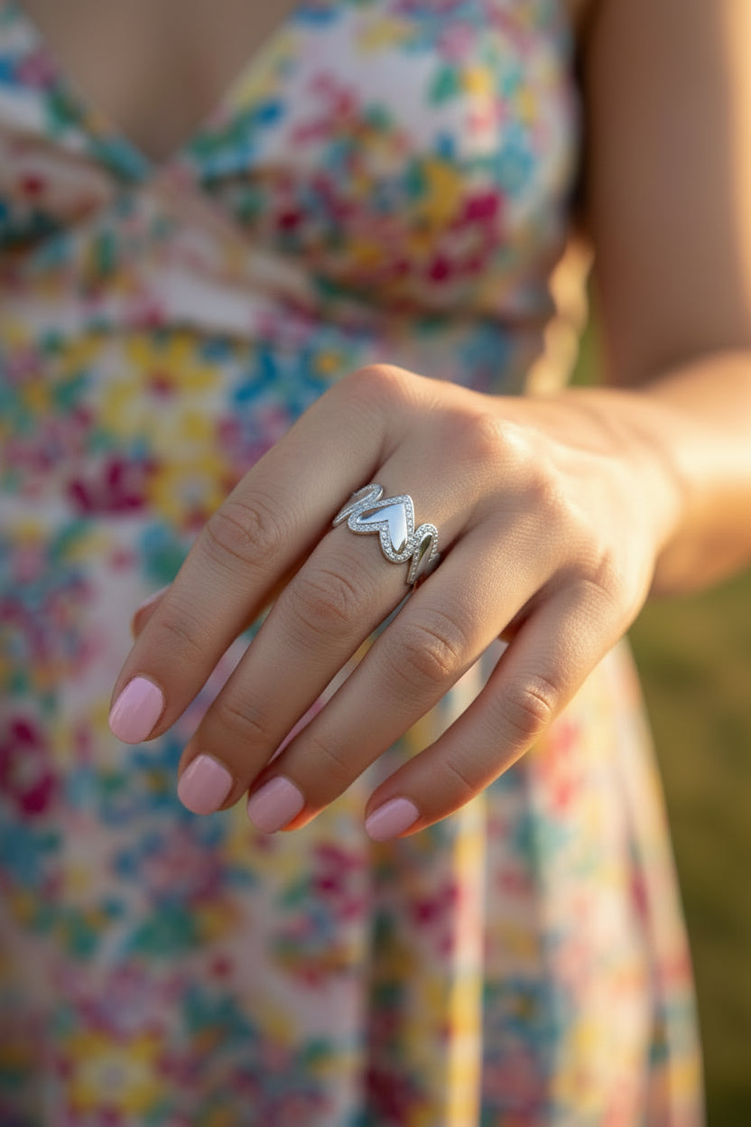 Luxe zilveren RVS harten ring gedragen aan de hand van een model met een zomerse bloemenjurk