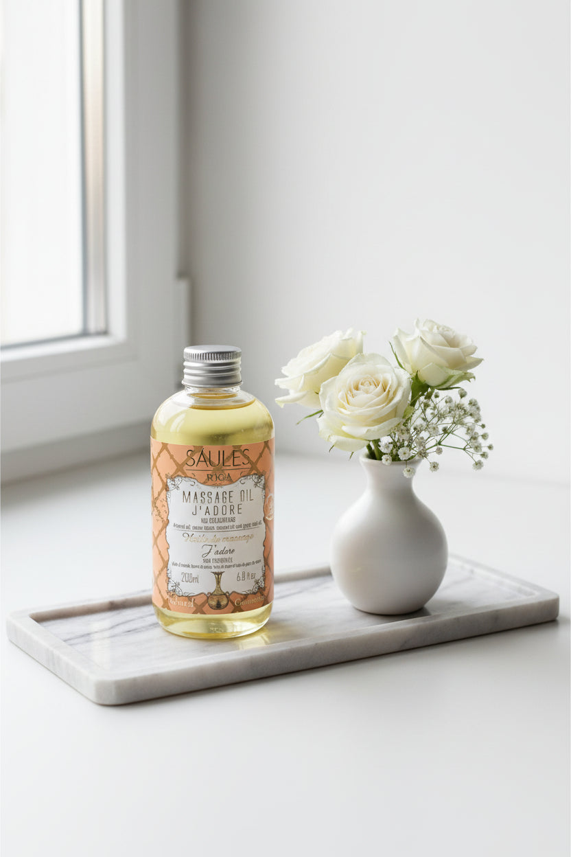 Saules Fabrika luxe massageolie J'adore 200ml doseerfles tegen een sfeervolle achtergrond met een grote witte bloemen en gipskruid - Glow Mystic in Style.
