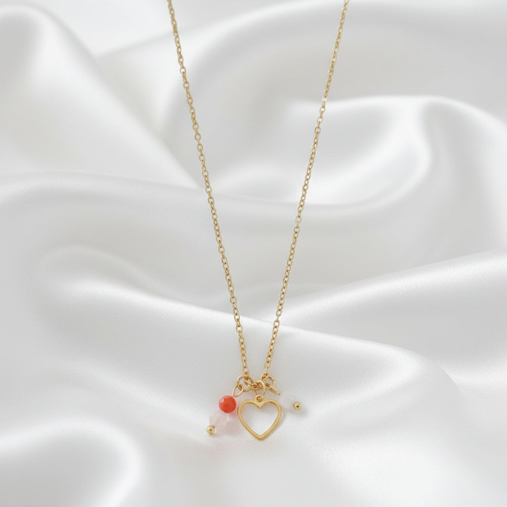 Detail van een kinderwens ketting met hartje en edelstenen op wit satijn.