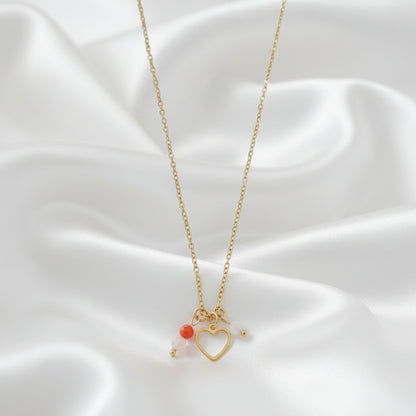 Detail van een kinderwens ketting met hartje en edelstenen op wit satijn.