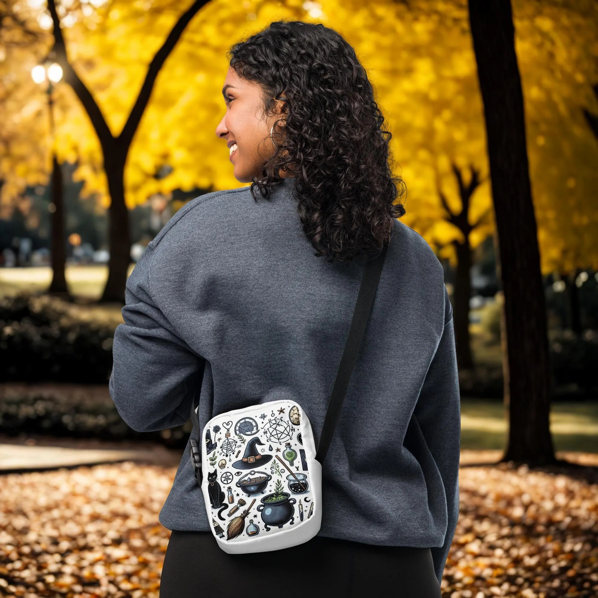Woman wearing a Witchy Halloween Crossbody Bag with witch-themed designs in an autumn park setting