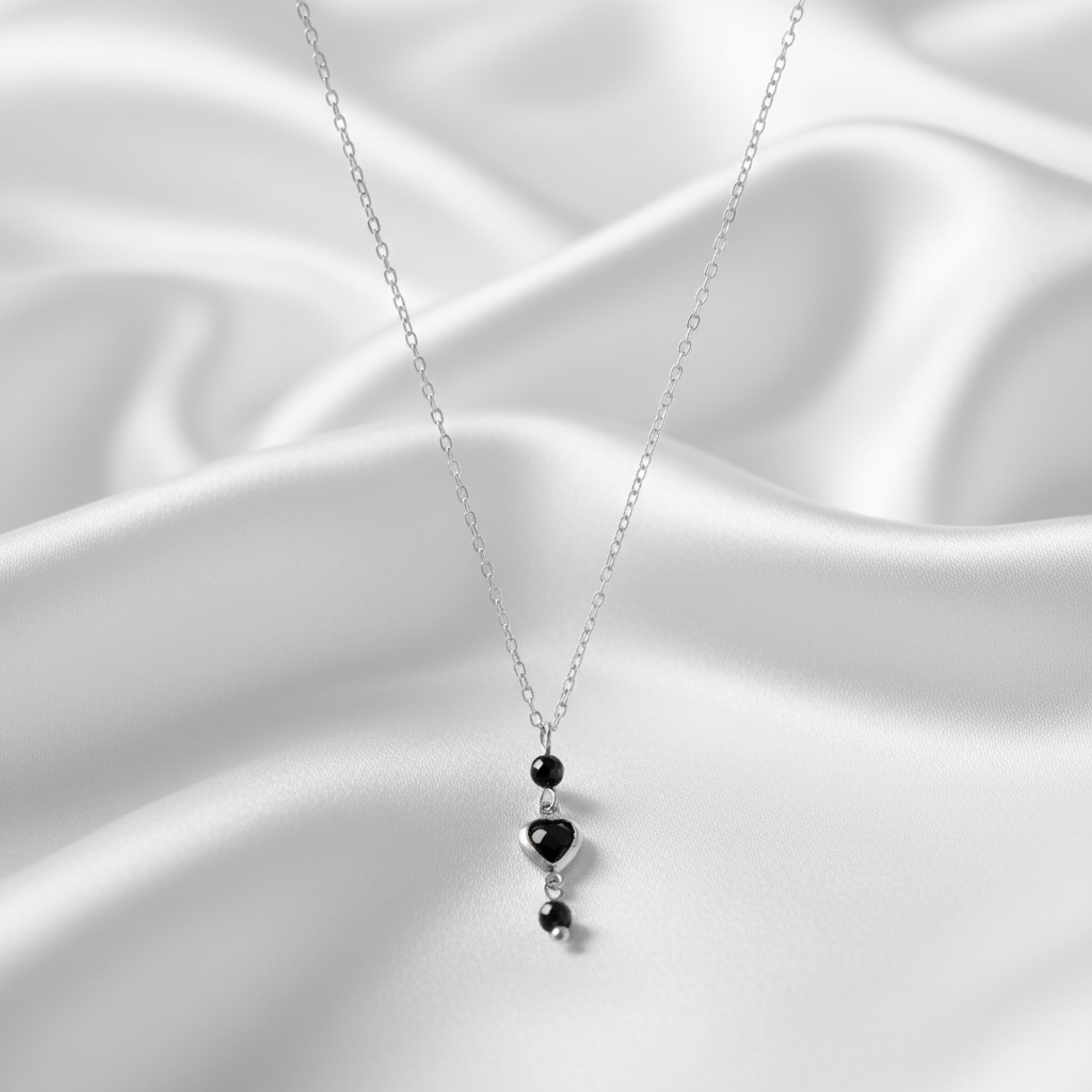 Zilveren ketting met zwart hartje op satijn achtergrond