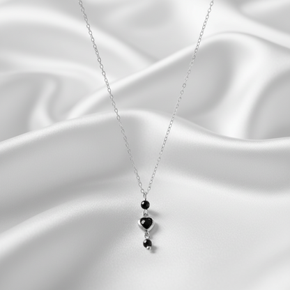 Zilveren ketting met zwart hartje op satijn achtergrond