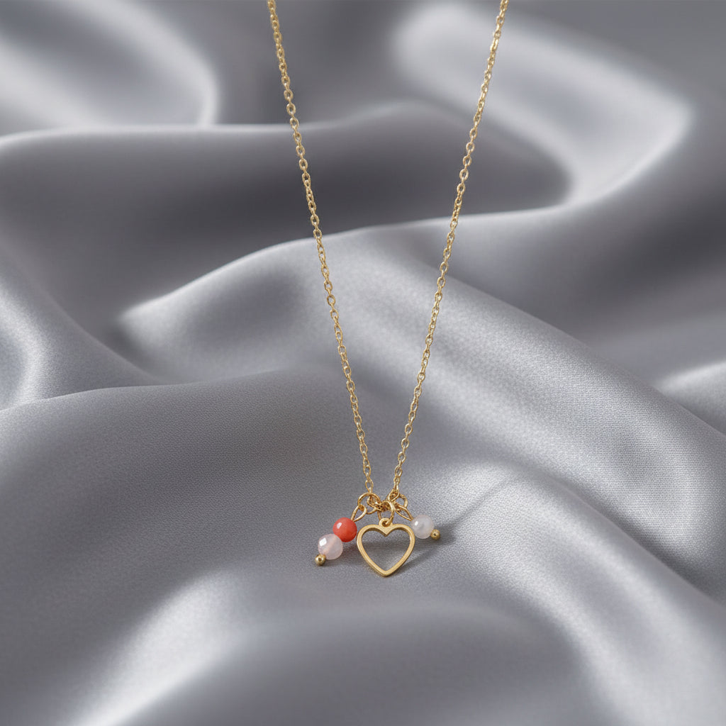 Kinderwens ketting met hartje, rozenkwarts, carneool en maansteen op grijs satijnen kleed.