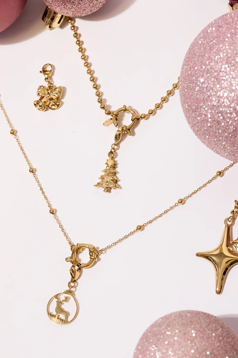 Stylingfoto van de gouden kerstboom bedel aan een ketting met roze kerstballen en kerstaccessoires