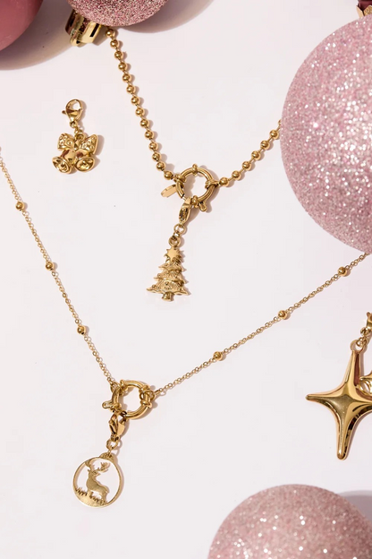 Stylingfoto van de gouden kerstboom bedel aan een ketting met roze kerstballen en kerstaccessoires