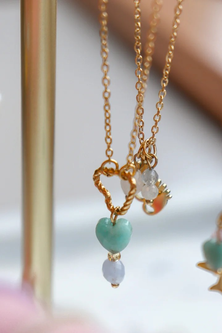 Glow Mystic in Style edelsteen ketting met gedraaid hartje getoond tussen andere gouden RVS kettingen