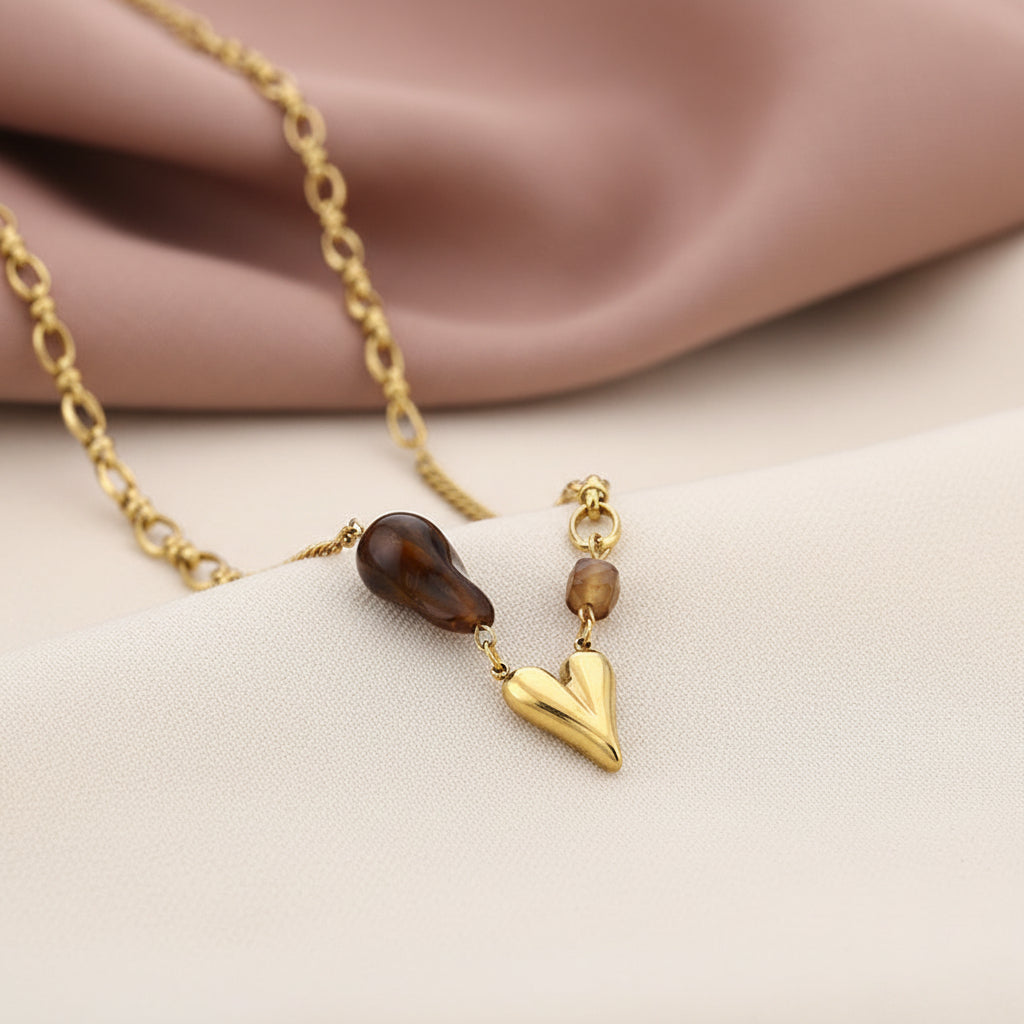 Glow Mystic in Style gouden ketting met bruine accentkraal op een zachte fluwelen achtergrond wit en oud roze kleur.