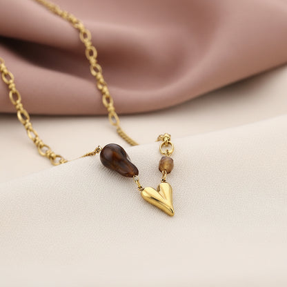Glow Mystic in Style gouden ketting met bruine accentkraal op een zachte fluwelen achtergrond wit en oud roze kleur.