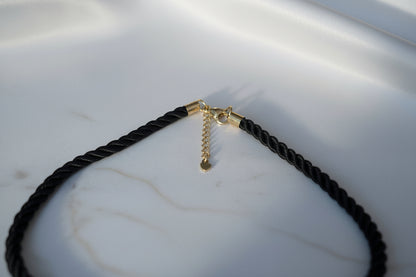 Zwarte statement ketting met goudkleurige bloemhanger voor dames.