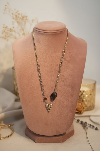 Close-up van de bruine organische kraal, facetkraal en het gouden 3D hartje aan de ketting op een oud roze buste