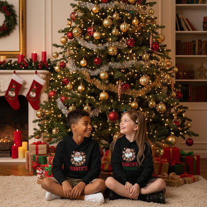 Children wearing black Santa's Little Helper Kids Hoodie with festive Santa design under a tree setting