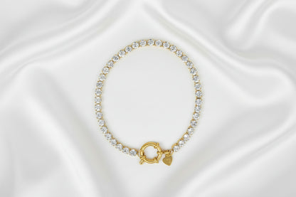 Gouden armband met sprankelende kristallen gepresenteerd op een marmeren ondergrond 