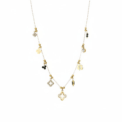 Verfijnde goudcolored RVS ketting met kleine klavertjes en zwarte kristallen, plat gefotografeerd als productfoto op een clean witte achtergrond.