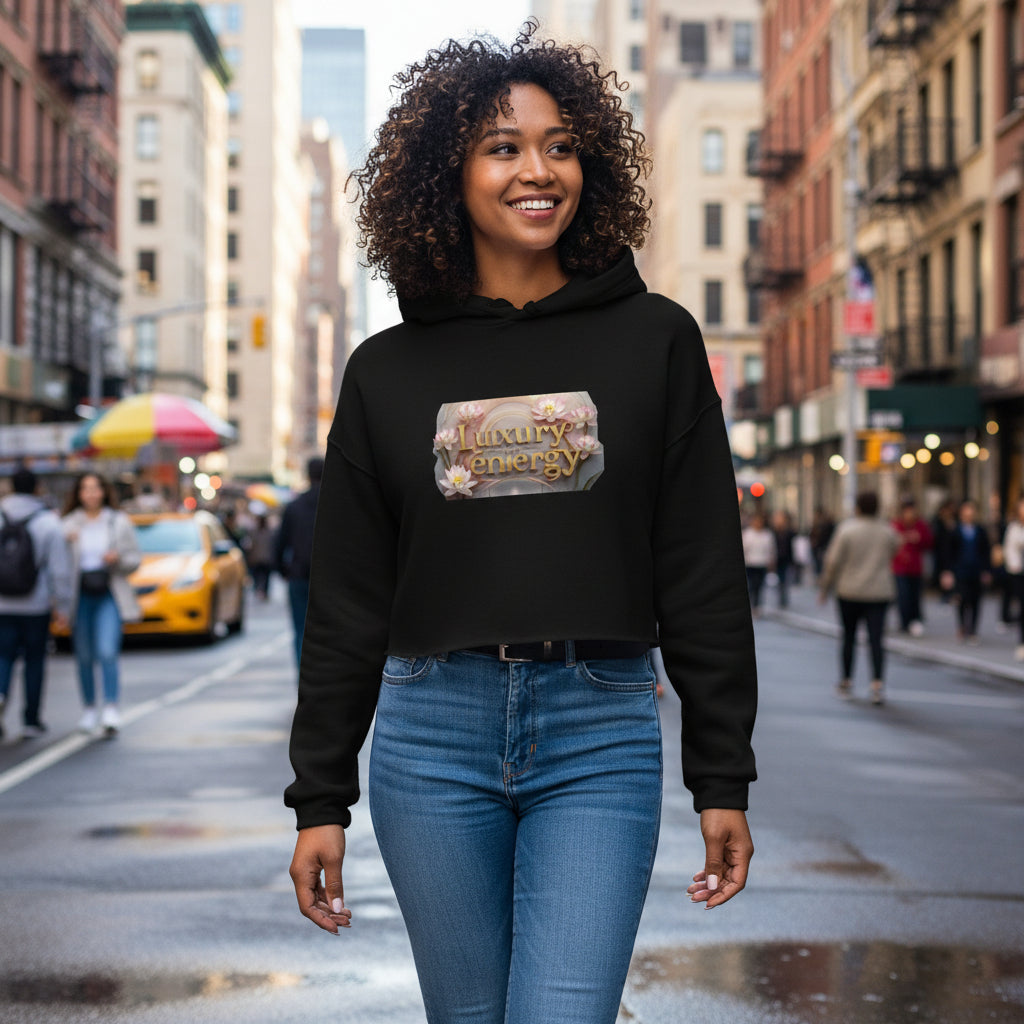Woman wearing black Luxury is My Energy Cropped Hoodie with floral logo print against gray textured wall