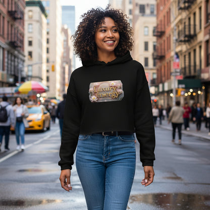 Woman wearing black Luxury is My Energy Cropped Hoodie with floral logo print against gray textured wall