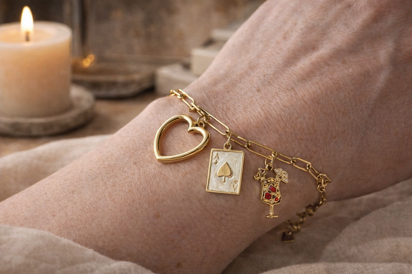 “Gouden bedelarmband met hart en speelse bedels gedragen om de pols, stijlvolle en luxe sieraden look voor vrouwen.”