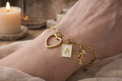“Gouden bedelarmband met hart en speelse bedels gedragen om de pols, stijlvolle en luxe sieraden look voor vrouwen.”