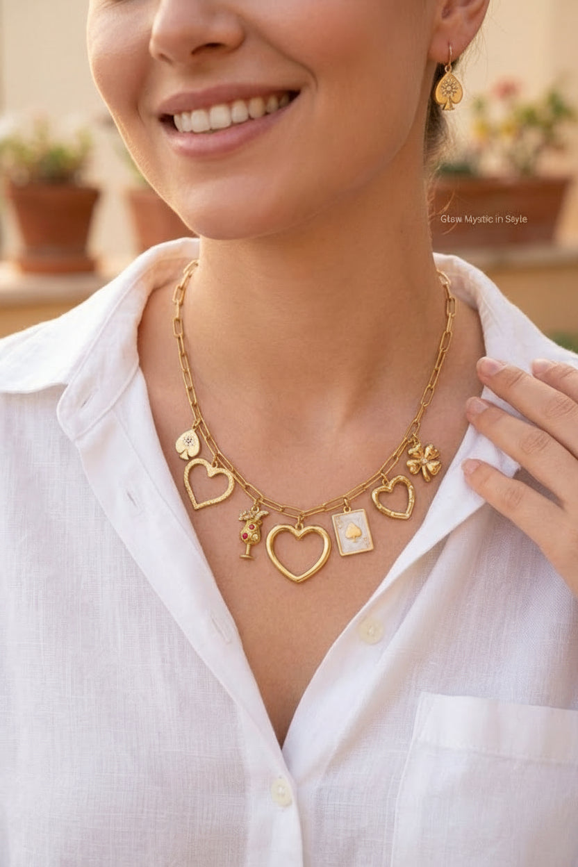 Een model met een witte linnen blouse draagt de goudkleurige RVS Vegas & Cocktail bedelketting met bijpassende oorbellen in een warme, zonnige setting.